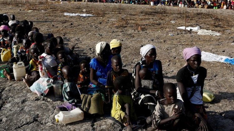 Women and children wait to be registered before a food distribution 